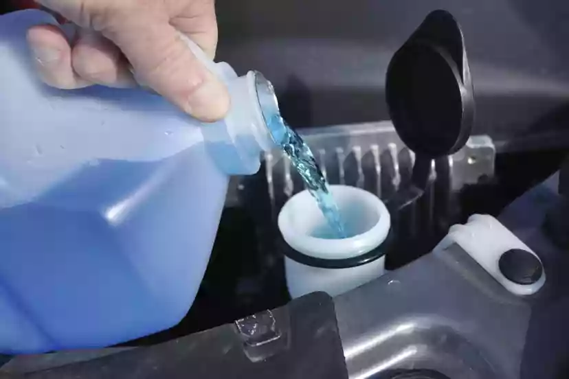 Pouring windshield wiper fluid into its reservoir