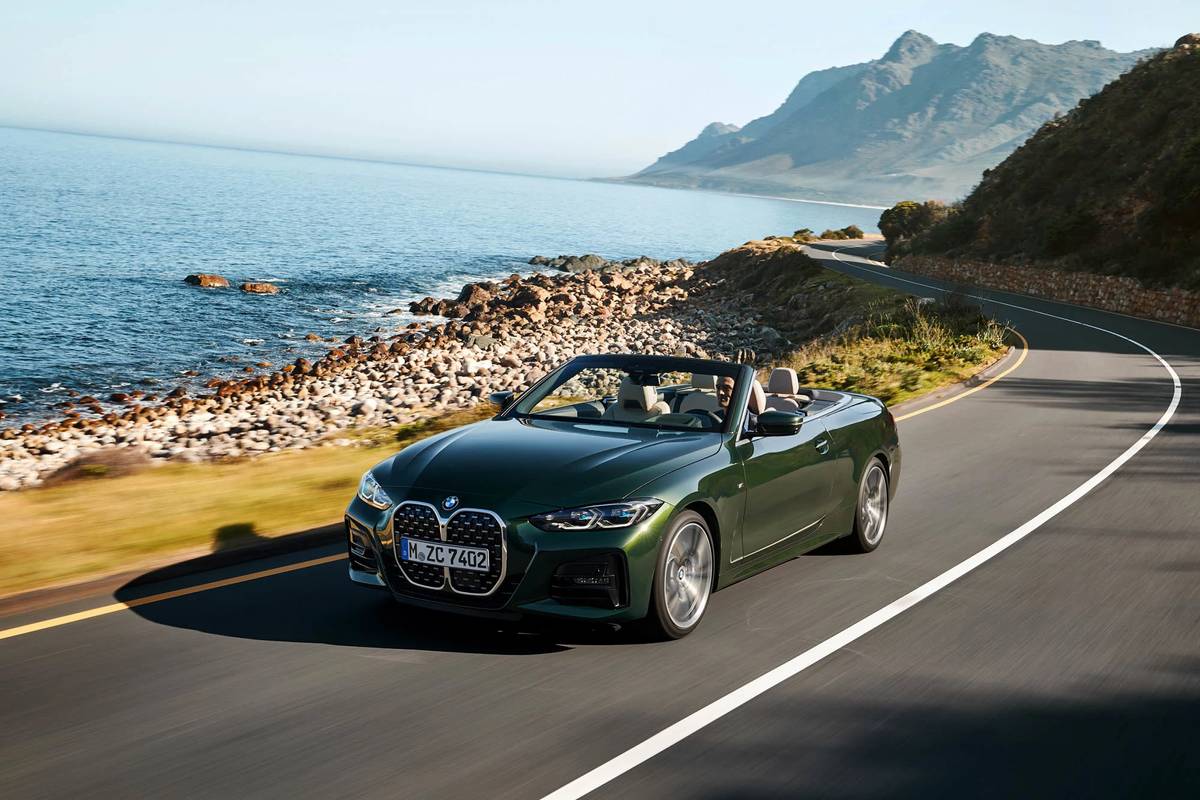 Green 2021 BMW 4 Series convertible driving on a waterside road
