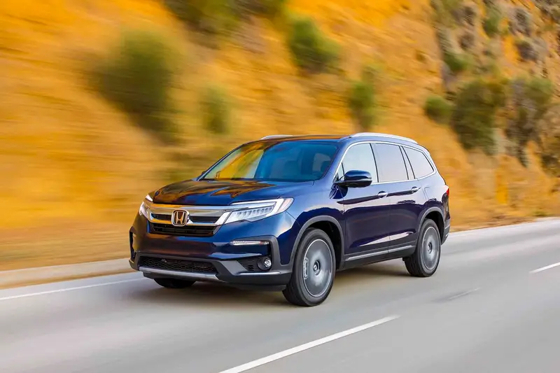 Front angle view of a blue 2021 Honda Pilot driving on a road