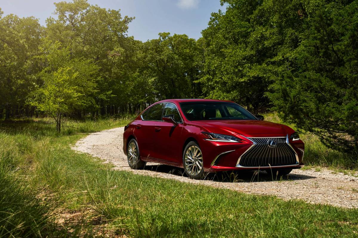 Front angle view of a red 2021 Lexus ES 250 driving on a winding dirt road