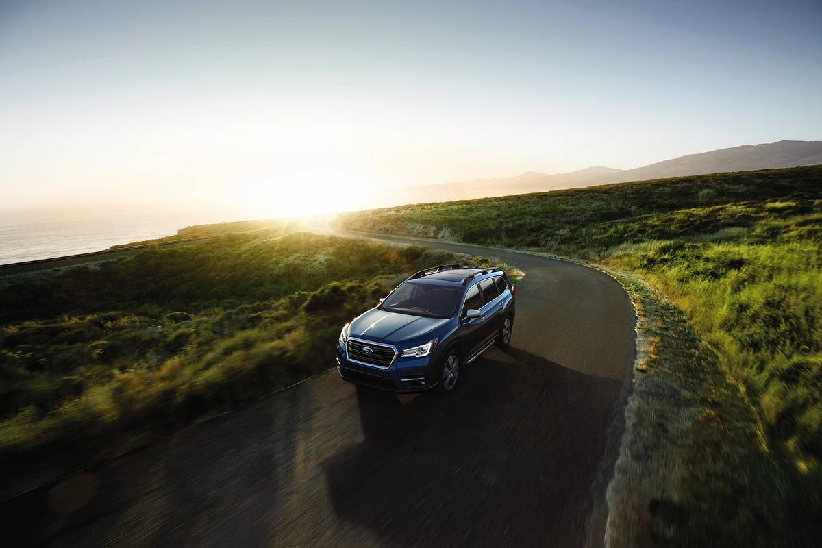 2021 Subaru Ascent driving around a bend in front of a sunset